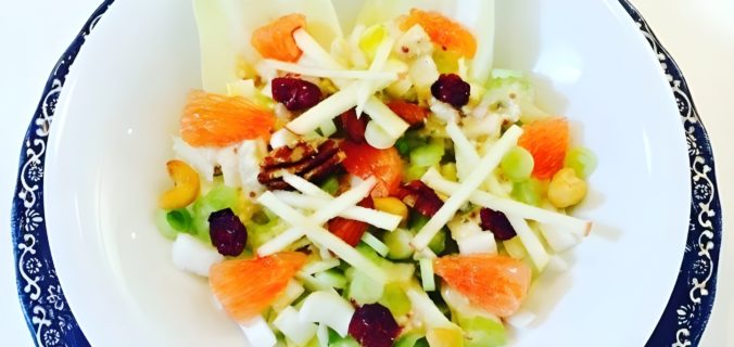 Frisse witlof salade met grapefruit, appel en noten op een wit bord