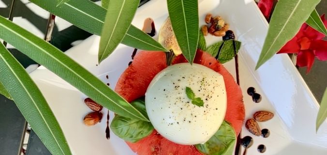Watermeloen burrata salade geserveerd op wit bord met verse kruiden - zomers voorgerecht recept